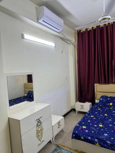 una camera da letto con un letto, un comò e uno specchio di Rawabi INN a Maţār al Malik Ḩusayn
