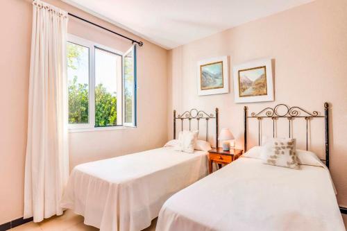 two beds in a room with a window at Villa Joel - Casa con piscina cerca de la playa in Son Carrio