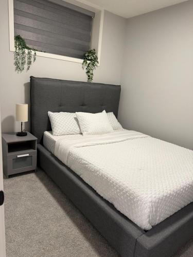 a bedroom with a large bed with white sheets at Relax, Recharge, Repeat 2Bedroom Walkout Haven in Calgary