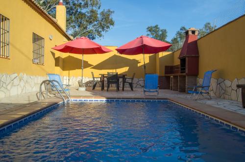 a swimming pool with umbrellas and chairs and a table at Rural Montes Málaga: Lagar Don Sancho in Málaga