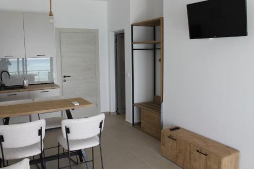 a kitchen with a table and chairs and a television at Villa Maria - Mola Suites in Kassandria