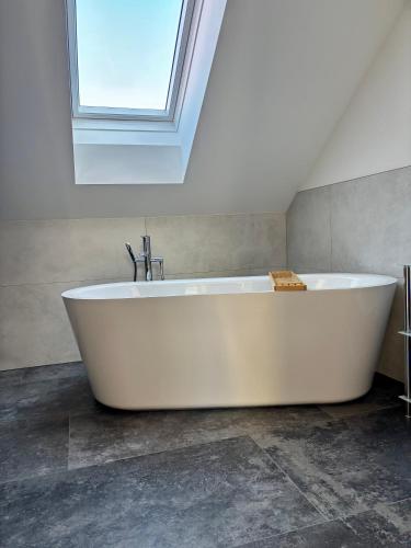 a white bath tub in a bathroom with a skylight at Gästehaus Seeblick Penthousewohnung in Seekirchen am Wallersee