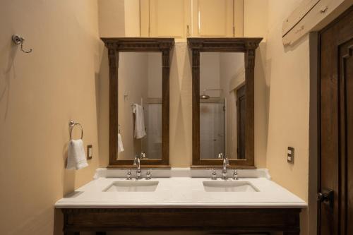 a bathroom with two sinks and two mirrors at Casa Alondra in Morelia