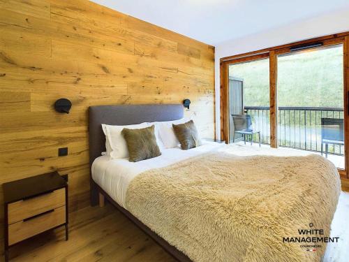 une chambre avec un grand lit avec un mur en bois dans l'établissement Résidence Ariondaz Hellebore - Superbe appartement exposé Sud au pied des pistes MAE-2554, à Courchevel