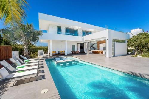 a villa with a swimming pool in front of a house at Oceanside 3 Bedroom Luxury Villa with Private Pool, 500ft from Long Bay Beach -V2 in Providenciales