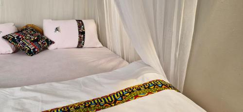 a bed with white curtains and pillows at 6 Engo Cottage - Benanda Forest Resort in Masaka