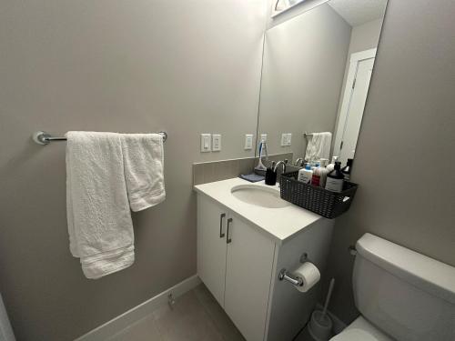 a bathroom with a sink and a toilet and a mirror at Cozzy & Brand New Apartment, Near Banff Hwy in Calgary
