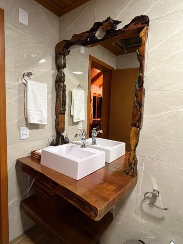 a bathroom with a white sink and a mirror at Chalé 2 - Cordilheira Dos Canyons in Praia Grande