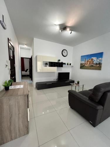 a living room with a couch and a clock on the wall at TJS Apartments 2 in Il-Gżira