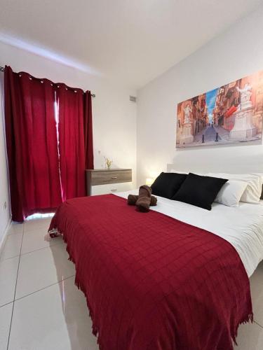 a bedroom with a large bed with a red blanket at TJS Apartments 2 in Il-Gżira