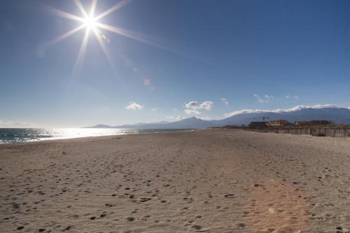 une plage avec des empreintes sur le sable et le soleil dans l'établissement Bel appartement côté Port avec Piscine & Tennis proche Plage, à Saint Cyprien Plage