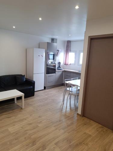 un salon avec un canapé noir et une cuisine dans l'établissement Chambre d'hôte confort - proximité directe Genève, à Annemasse