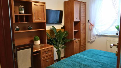 a bedroom with a bed and a desk and a tv at Apartament Zielona Przystań u Agi in Ełk