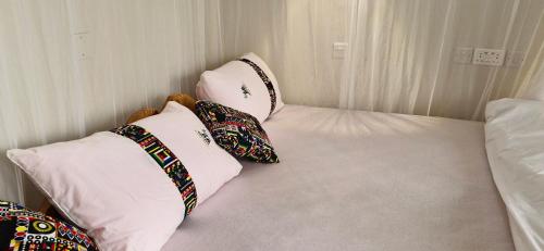 a bed with four pillows on it in a room at 5 Empologoma Cottage - Benanda Forest Resort in Masaka