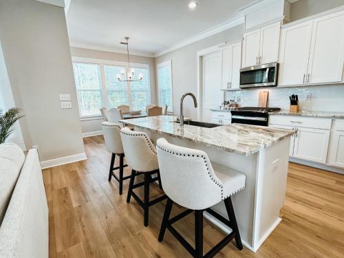 a kitchen with white cabinets and a kitchen island with bar chairs at High Tides in Orange Beach