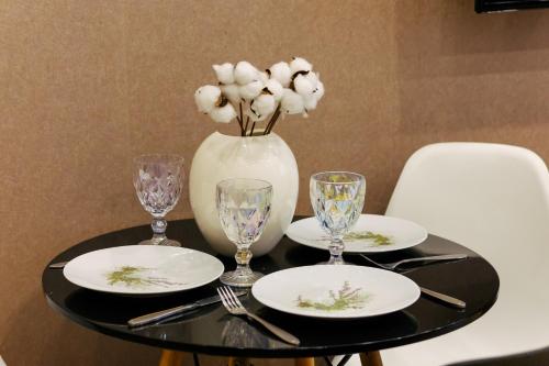 a table with plates and glasses and a vase with flowers at Residence North Avenue, Teryan 8. 14 2 in Yerevan