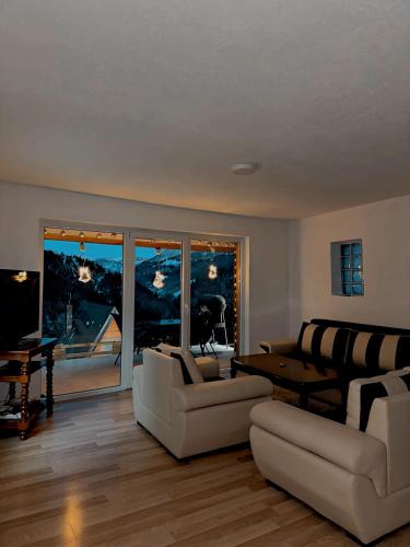 a living room with white furniture and a large window at Rugova's Paradise Villas in Peje