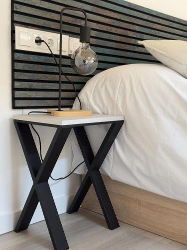a black lamp on a table next to a bed at VUT La Casa de la Vega in El Barraco