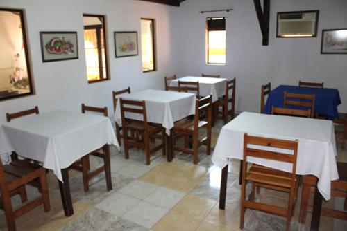 uma sala de jantar com mesas brancas e cadeiras de madeira em Pousada Boa Vista em Brotas