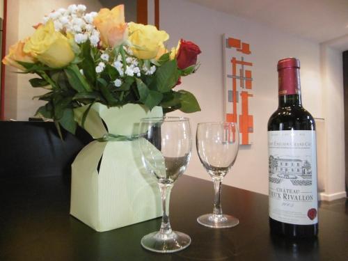 - une bouteille de vin à côté de deux verres et d'un vase de fleurs dans l'établissement Le clos d'Ondres-Spa, à Sarrant