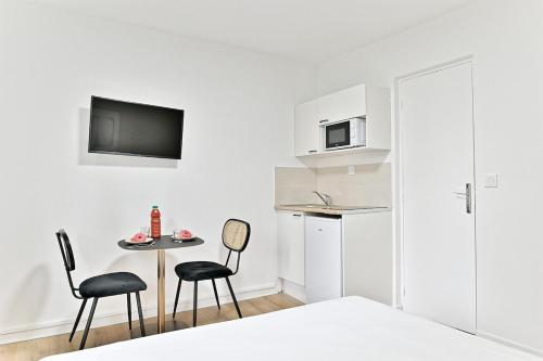 une petite cuisine blanche avec une table et deux chaises dans l'établissement Charming little studio close to Paris- III, à Asnières-sur-Seine