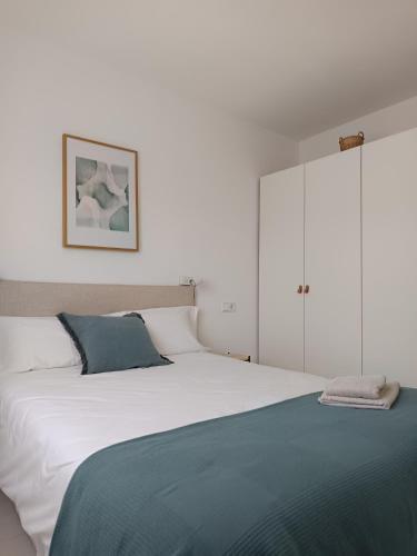a bedroom with a large white bed with a blue blanket at Camí Ample, Apartamento 2 hab con parking in L'Escala
