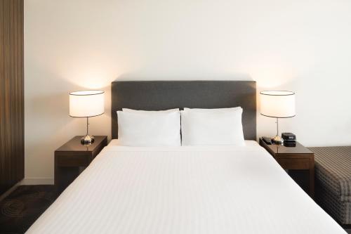 a bedroom with a large white bed with two lamps at The Sebel Melbourne Kew in Melbourne