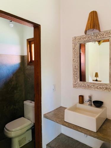 a bathroom with a sink and a toilet and a mirror at Chalés Casulo Caraíva in Caraíva