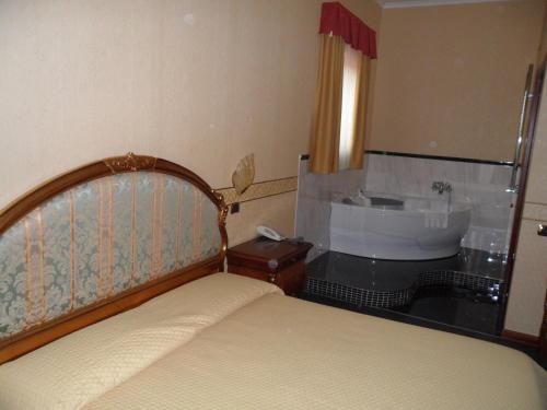 a bedroom with a bed and a sink and a tub at Hotel Ai Sette Nani in Sistiana