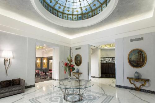 un salon avec une table en verre et un plafond dans l'établissement Hotel Artemide, à Rome