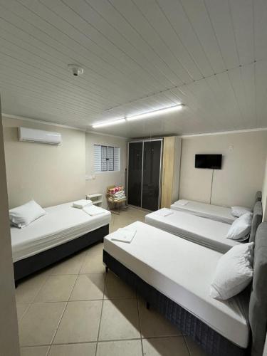 a room with two beds and a tv on the wall at Pousada da Jô in São Gabriel