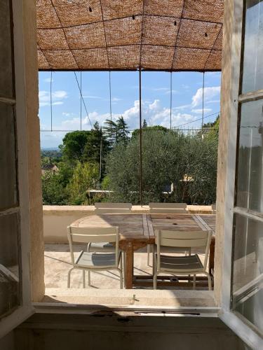 une table et des chaises devant une grande fenêtre dans l'établissement Bastide de charme - Les Arcades, à Sablet