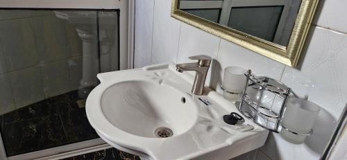 a white sink in a bathroom with a mirror at 2 Envubu Cottage - Benanda Forest Resort in Masaka
