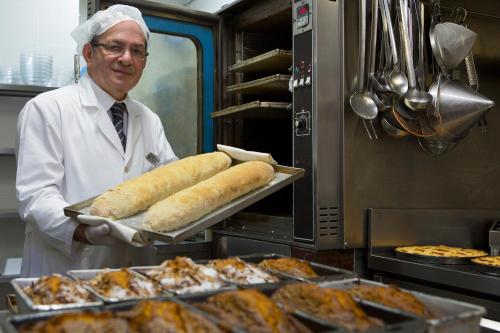 a man is holding a tray of food in a kitchen at Hotel Artemide in Rome