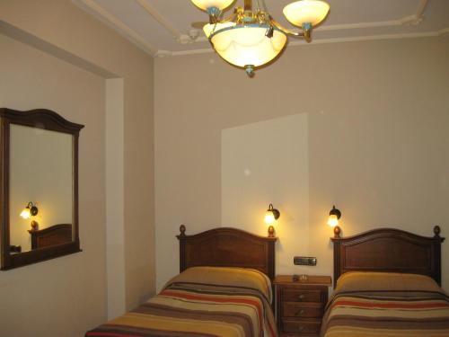 a bedroom with two beds and a mirror at Hostal Granada in Salamanca