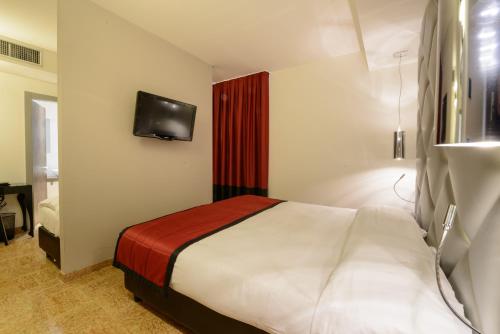 a bedroom with a bed and a tv on the wall at Corte Ongaro Hotel in Verona
