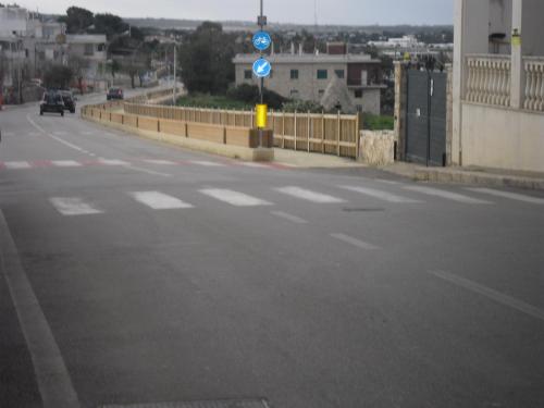 an empty road with a blue sign in the middle at Dimora Dei Gelsi in Polignano a Mare