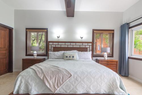 a bedroom with a large bed and two windows at Updated Beachfront Paradise Infinity Pool Roatan in Palmetto Bay