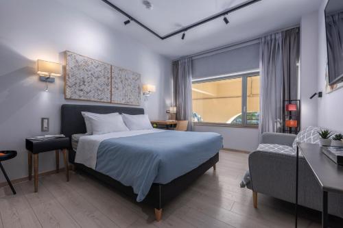 a bedroom with a bed and a chair and a window at Square Elegant Suites in Thessaloniki