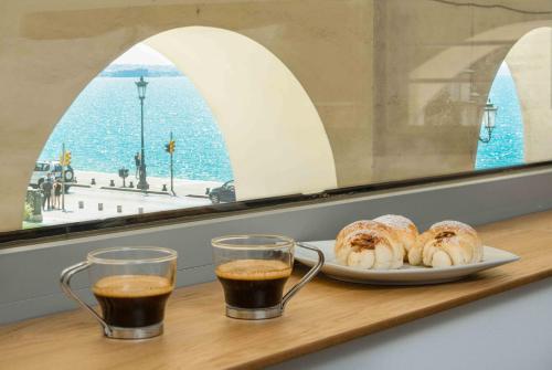 a table with a plate of pastries and two glasses of coffee at Square Elegant Suites in Thessaloniki