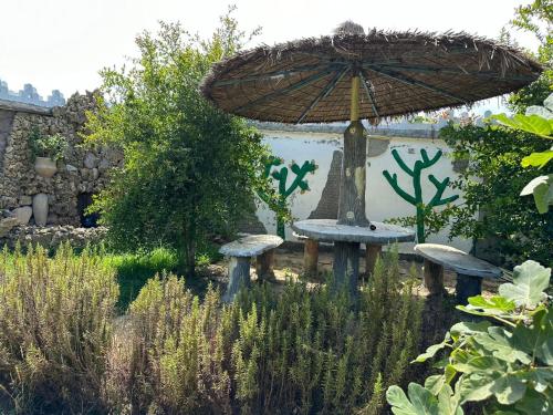 a table with an umbrella and benches in a garden at Charmante Villa à Rmilat Plage in Asilah