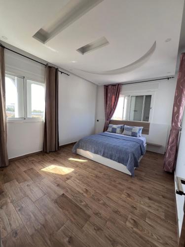 a bedroom with a bed and two windows at Charmante Villa à Rmilat Plage in Asilah