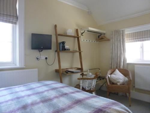 a bedroom with a bed and a tv and a chair at The Maples in Hythe