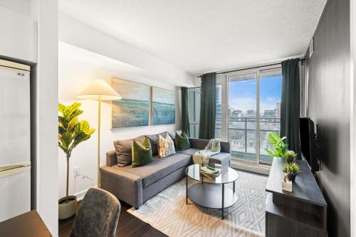 a living room with a couch and a large window at Modern 1BR King Suite, Central Downtown Toronto in Toronto