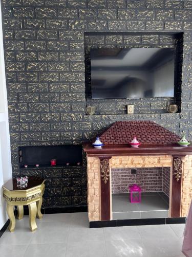 a living room with a fireplace and a tv on a wall at Charmante Villa à Rmilat Plage in Asilah
