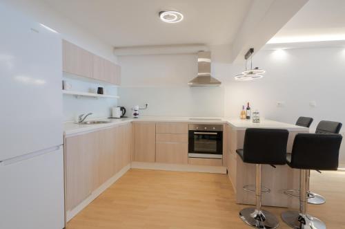 a kitchen with white counters and black chairs at Bjelasnica Mountain Retreat in Bjelašnica