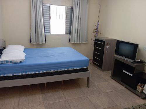 a small bedroom with a bed and a television at Casa completa Estância Turística de Ribeirão Pires in Ribeirão Pires