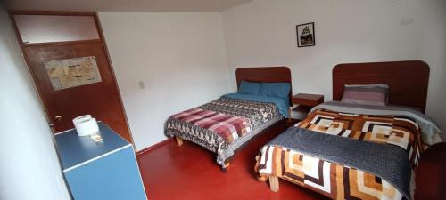 a room with two beds and a refrigerator at Hospedaje Vacacional - Colca in Chivay