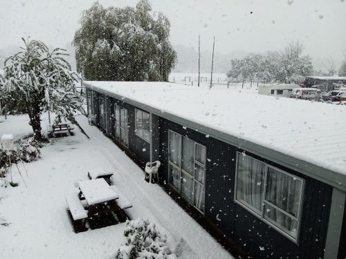 a house covered in snow with a dog standing on the roof at Mt Dobson Motel in Kimbell