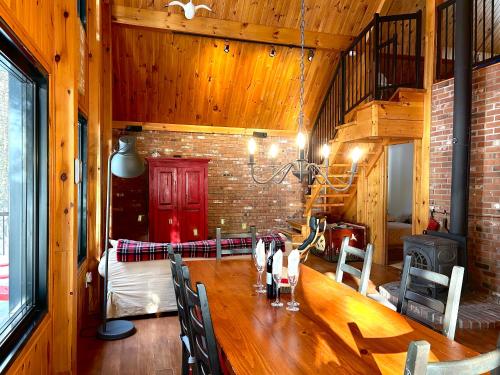 a dining room with a wooden table and a fireplace at Winter Lakefront Chalet - Serendipity Hideaway - Ski, Skate, Snowshoes & Relax by the Cozy Fire in Chertsey